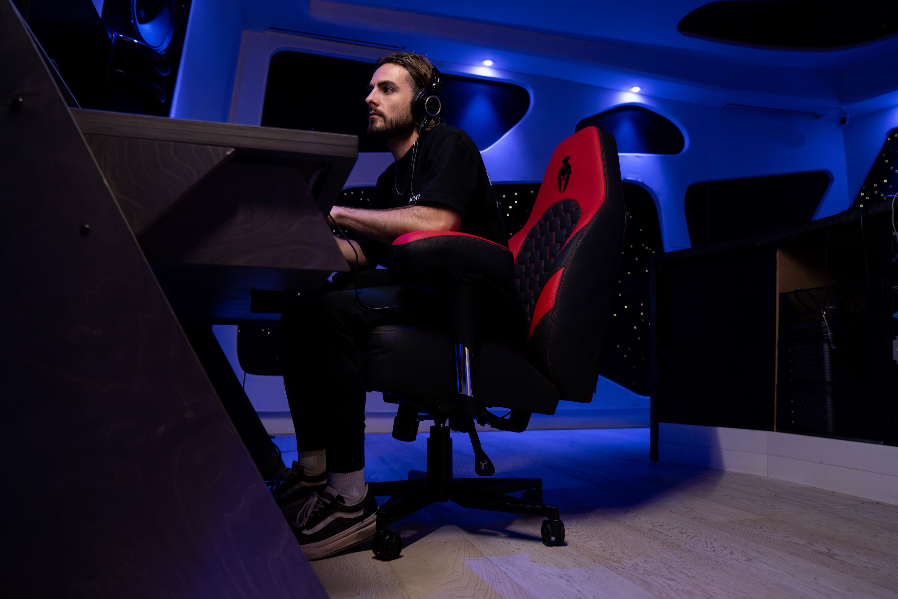 Studio producer sitting on a red and black gaming chair with haptic feedback